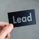 Black Business Card with the Word Lead on it